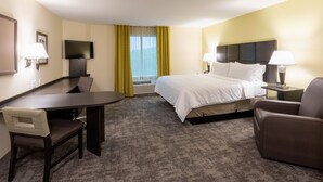 A hotel room with a bed, two chairs, a desk, a TV, and a window with curtains. - Candlewood Suites Rochester Mayo Clinic Area by IHG (Rochester)