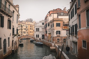 Un canal étroit, avec des bateaux, un pont et des bâtiments dotés de balcons et de fenêtres.