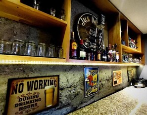 A bar area with shelves stocked with bottles, a sign indicating no working during drinking hours, and a sign warning against quitting. - Mika Suites (Bogotá)