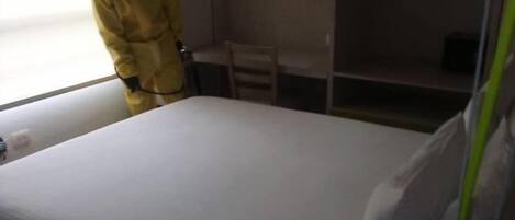 Een kamer met een bed, nachtkastje en een raam.