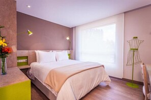 A modern hotel room with a bed, bedside lamps, a window, and a green floor lamp. - Mika Suites (Bogotá)