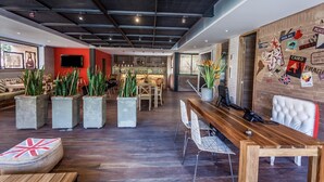 A modern interior with a wooden reception desk, seating area with potted plants, and a wall adorned with travel-themed stickers. - Mika Suites (Bogotá)