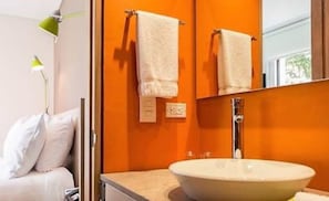 A bathroom with a white sink, two towels hanging on a towel rack, a mirror, and a green lamp. - Mika Suites (Bogotá)