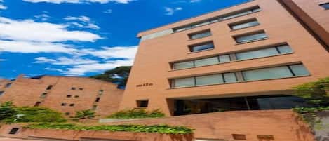Un edificio de varios pisos con fachada de ladrillo, ventanas grandes y la palabra 'mila' en el lateral.