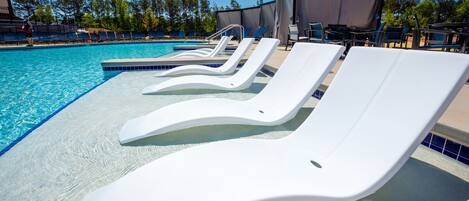 Una piscina con sillones blancos y una zona cubierta.