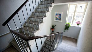 Eine Treppe mit Metallgeländer, einem Blumentopf und einem Fenster mit Blumen.