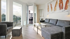 A modern living room with grey sofas, a coffee table, and a large window.