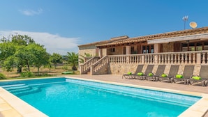 Une piscine avec un bâtiment en pierre en arrière-plan, un escalier et une rangée de chaises longues.