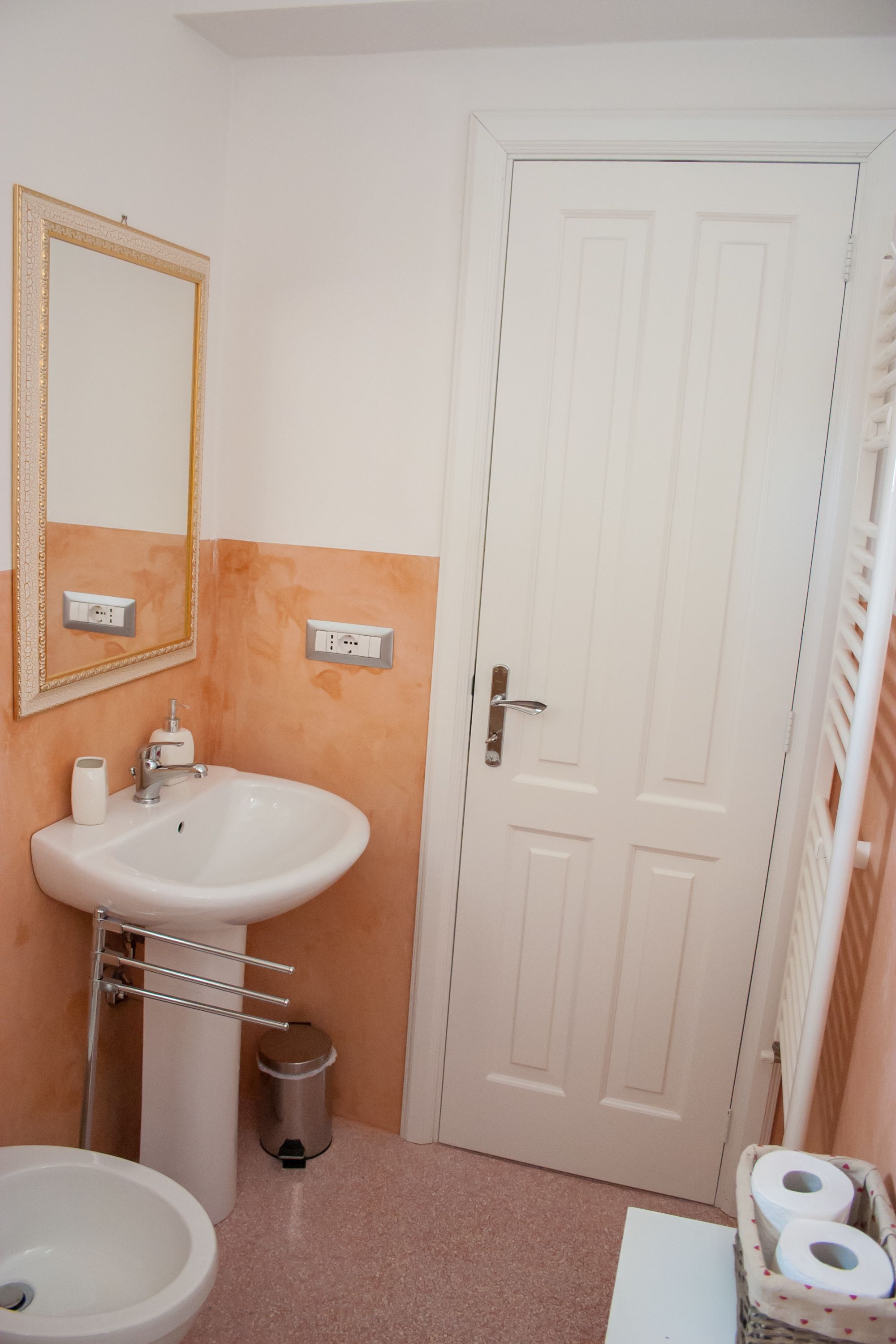 Une salle de bain avec un lavabo, un miroir, des toilettes et une porte.