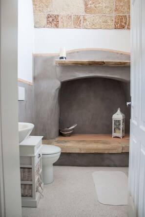 A bathroom with a stone wall, a white sink, a toilet, and a white lantern. - Riz Salento Guest House (Montesano Salentino)