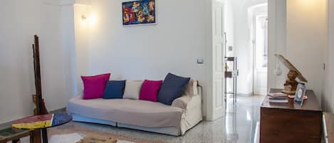Una sala de estar con un sofá, una mesa de madera, un banco y un escritorio con una lámpara.