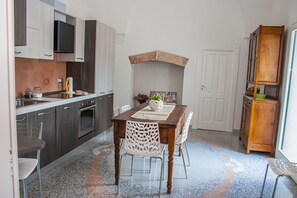 A modern kitchen with dark cabinetry, a built-in oven, and a dining area with a wooden table and chairs. - Riz Salento Guest House (Montesano Salentino)