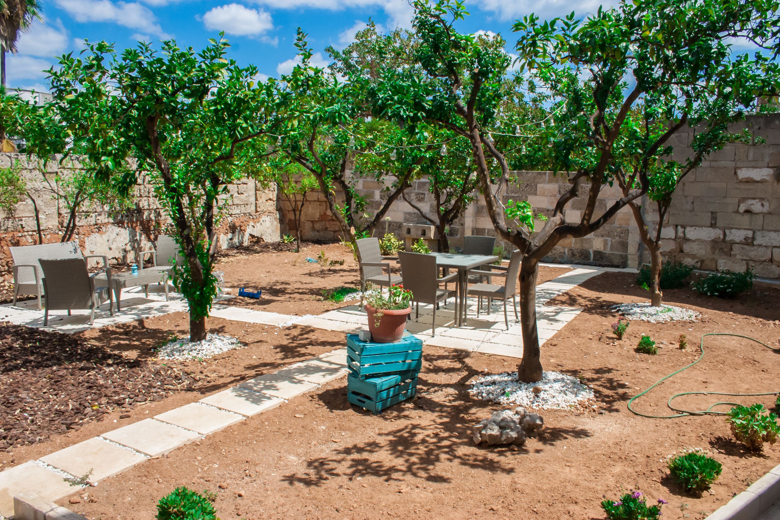 An outdoor patio area with seating, potted plants, and a garden bed.