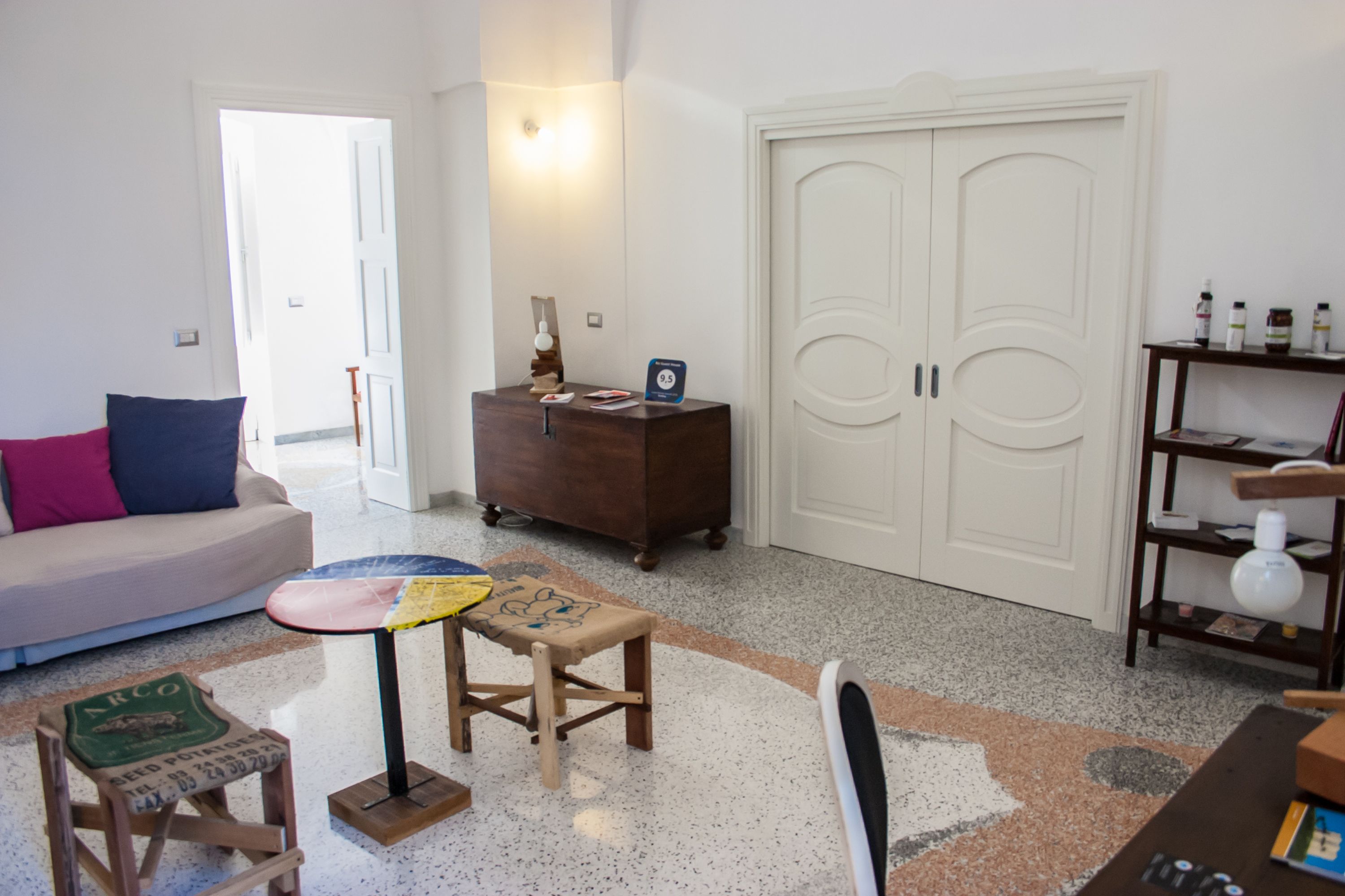 Ein Wohnzimmer mit einer Couch, einem kleinen Tisch, einem Holzschrank und einem Bücherregal.