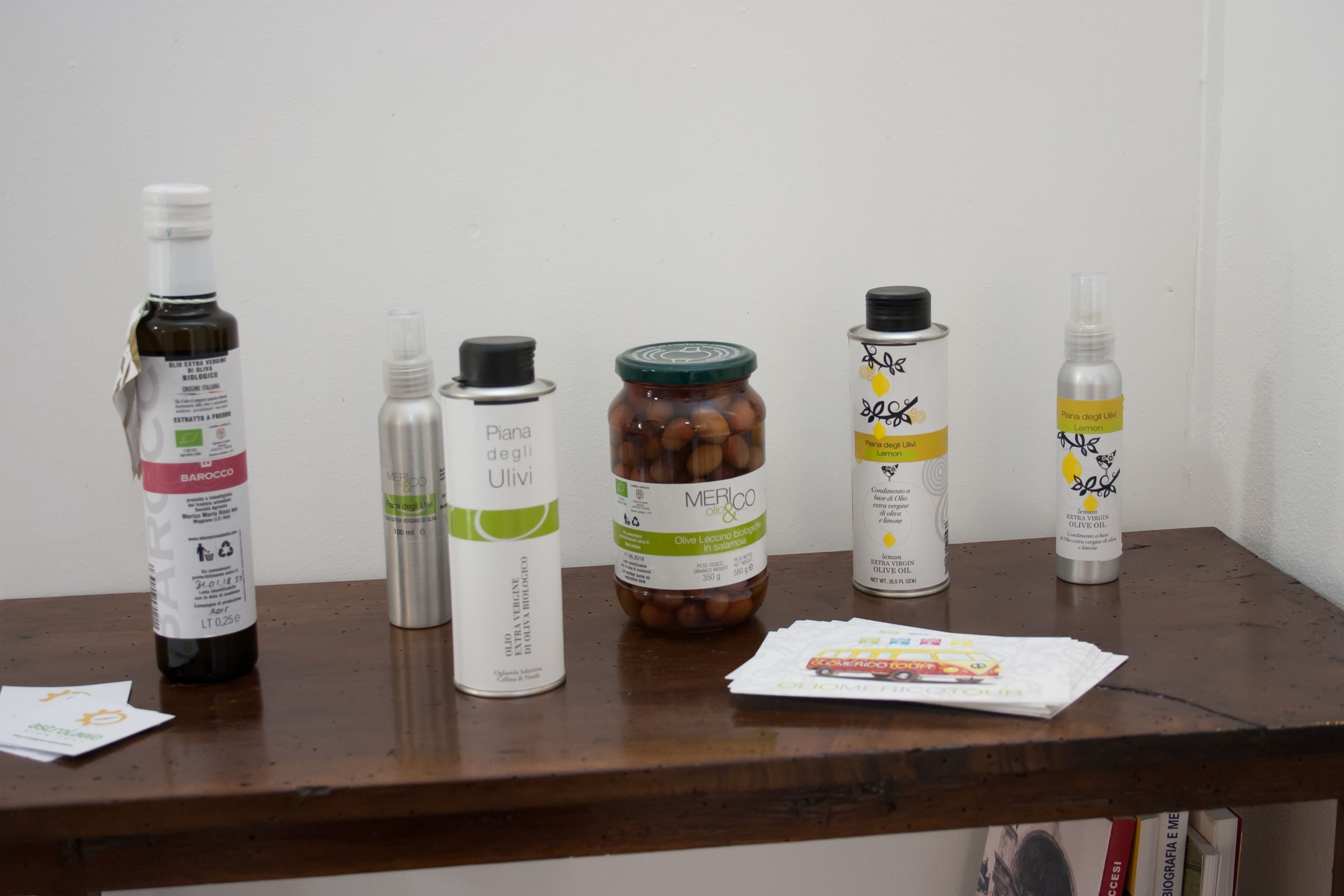A wooden table with various bottles and a jar of olives.