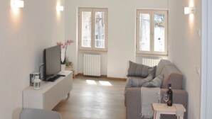 Un salon moderne avec un canapé, un téléviseur et une petite table sur laquelle se trouvent une bouteille et un verre.