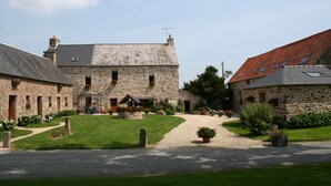A stone building with a gravel driveway and a well-maintained lawn. - Ecuries de Kerbalan Gîtes à la ferme (Gommenec'h)