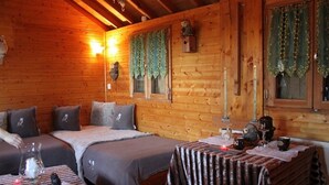 A cozy cabin-style room with two beds, a small table with a candle, and wooden walls. - Ecuries de Kerbalan Gîtes à la ferme (Gommenec'h)