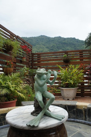 A statue of a frog on a marble pedestal in a garden setting with potted plants and a wooden fence. - Cheng-Ping Hot Spring Inn (Taimali)
