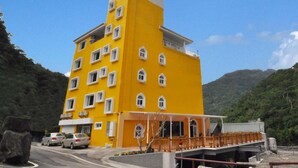 Un edificio amarillo de varios pisos con techo plano, varias ventanas y un balcón.