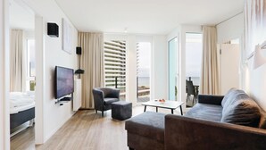 Ein modernes Hotelzimmer mit einem großen Bett, einem Fernseher, einer Couch und einem Balkon mit Blick auf die Stadt.