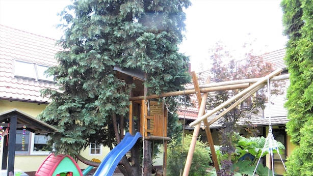 A playground with a slide, swings, and a small house. - Müller's Landidyll - Apartments Müller's Landidyll (Klitten)