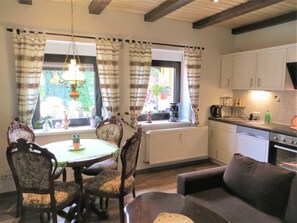 Un coin repas avec une table et des chaises, une cuisine équipée et une fenêtre avec des rideaux.