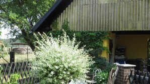 A garden with a variety of plants, a large planter, and a brick structure. - Müller's Landidyll - Apartments Müller's Landidyll (Klitten)