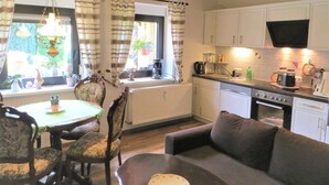 A cozy kitchen with a dining area, wooden beams, and a sofa. - Müller's Landidyll - Apartments Müller's Landidyll (Klitten)