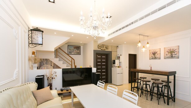 A spacious living area with a white sofa, a dining table, and a kitchen area with bar stools. - Love 300 (Luodong)