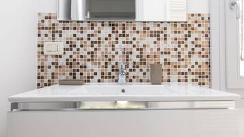 A bathroom with a white sink, a modern faucet, and a tiled backsplash.