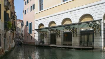 Un edificio a orillas de un canal, con un paseo techado y ventanas de arco.