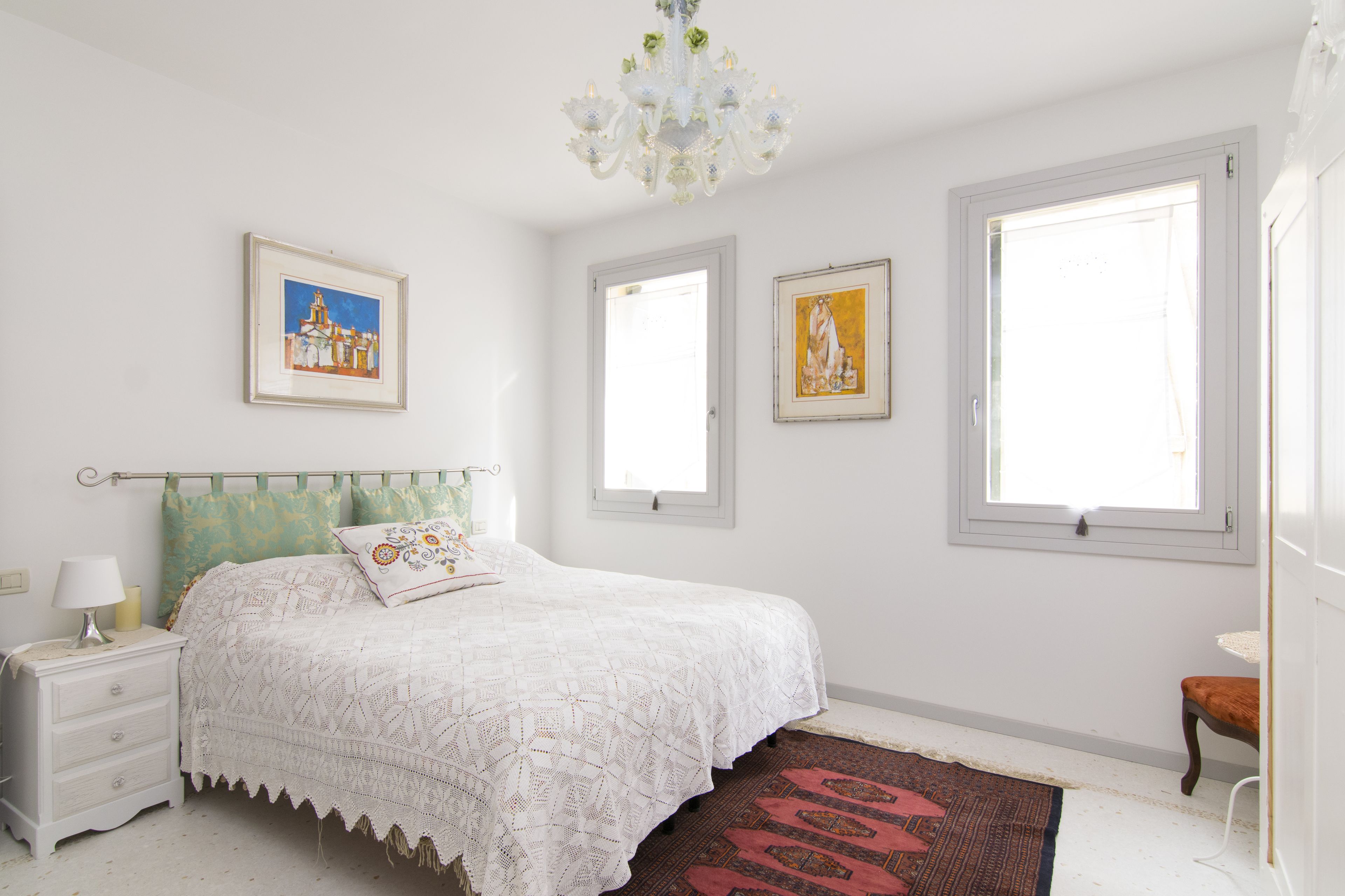 A bedroom with a bed, nightstand, and a window.