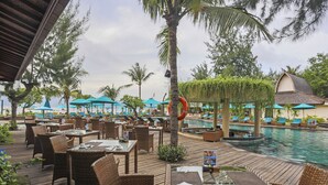 A resort pool area with lounge chairs, dining tables, and a pool. - Akoya Pool Villa (Gili Trawangan)