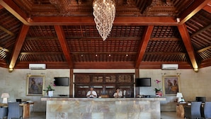 A reception area with a marble counter, wooden ceiling, and two receptionists. - Akoya Pool Villa (Gili Trawangan)