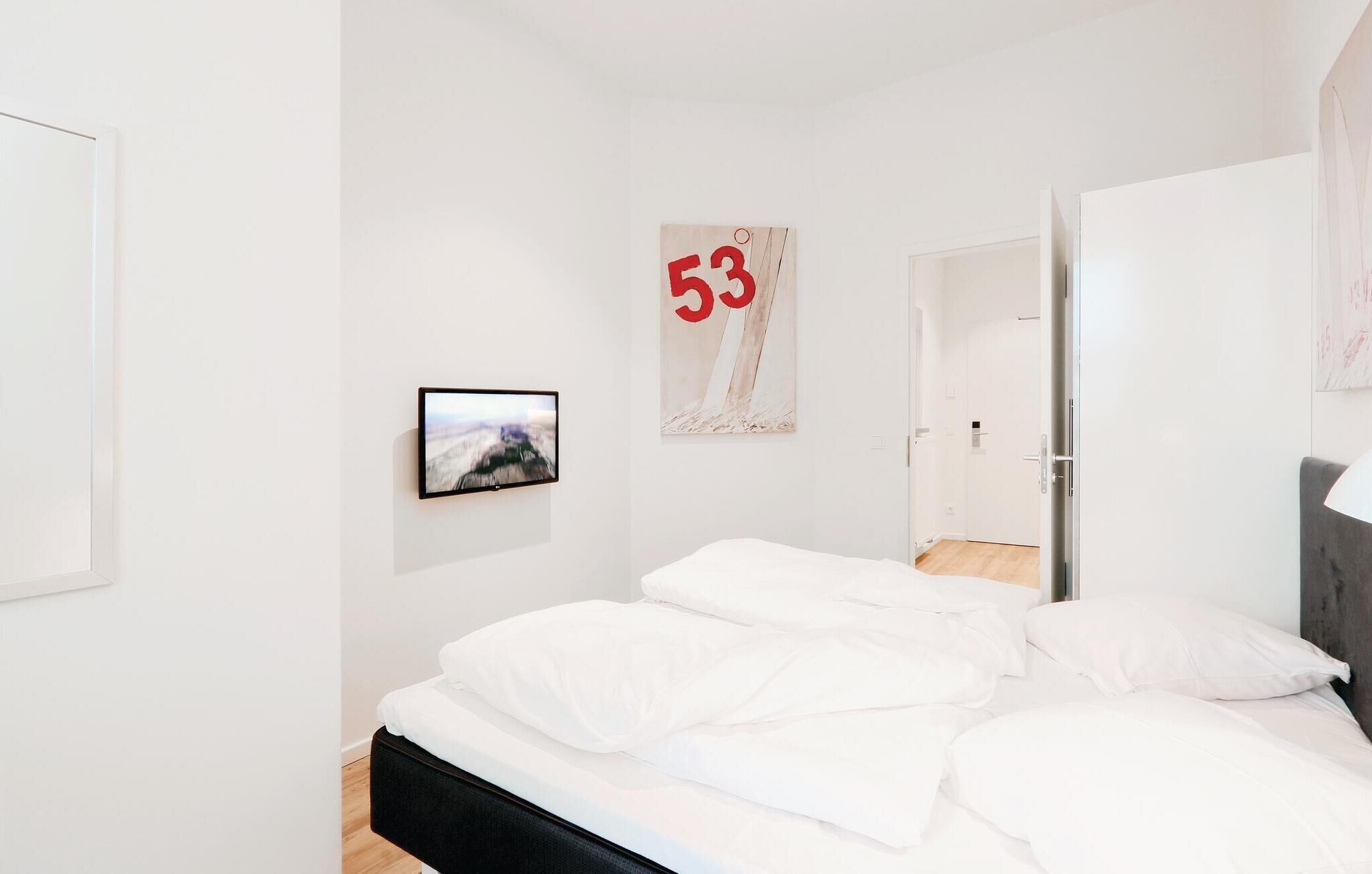 Ein schlicht eingerichtetes Schlafzimmer mit einem Bett, einem gerahmten Bild und einer Tür.