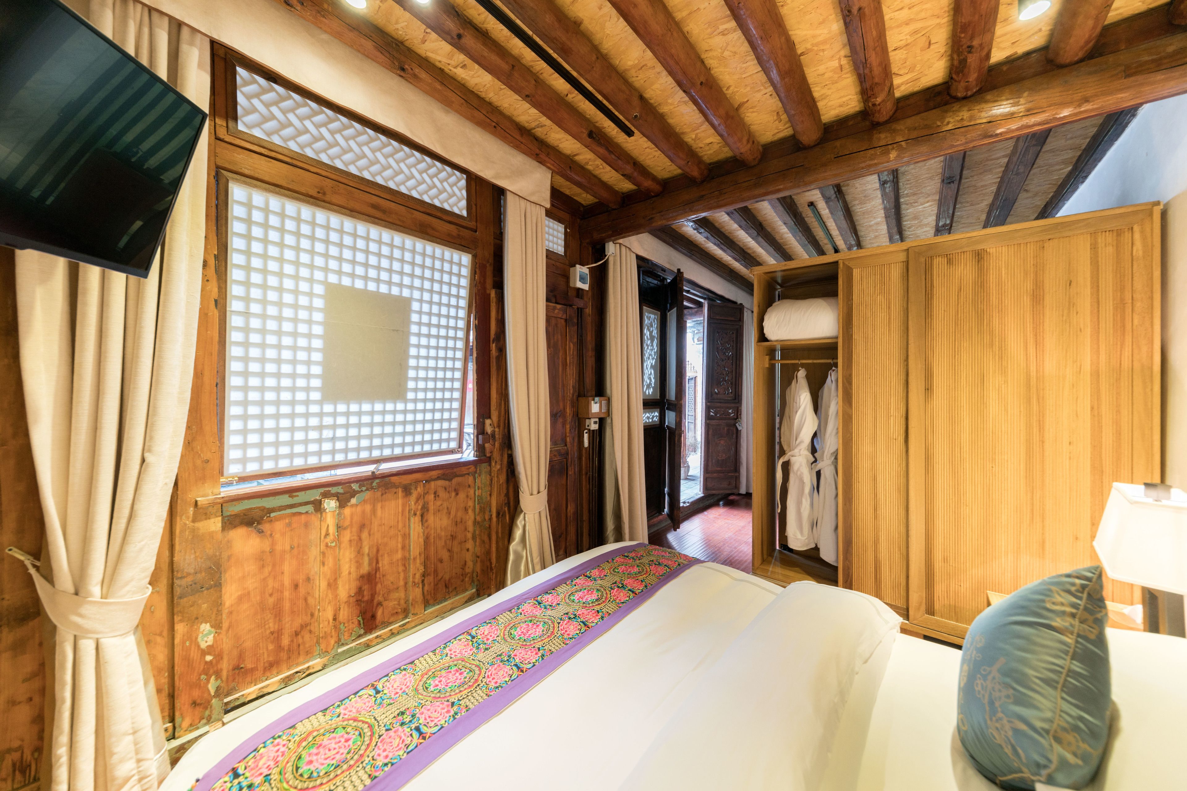 Ein traditioneller japanischer Raum mit Tatami-Böden, einer Futon-Liege, Schiebetüren und einem an der Wand befestigten Fernseher.