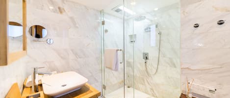 Un bagno moderno con doccia vetrata, un mobile contenitore in legno e pareti in marmo.
