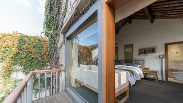 Un dormitorio con una ventana grande, una cama de madera, una mesita de noche y vistas a un jardín.