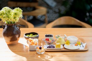 A wooden table with a variety of food items and a vase of flowers.