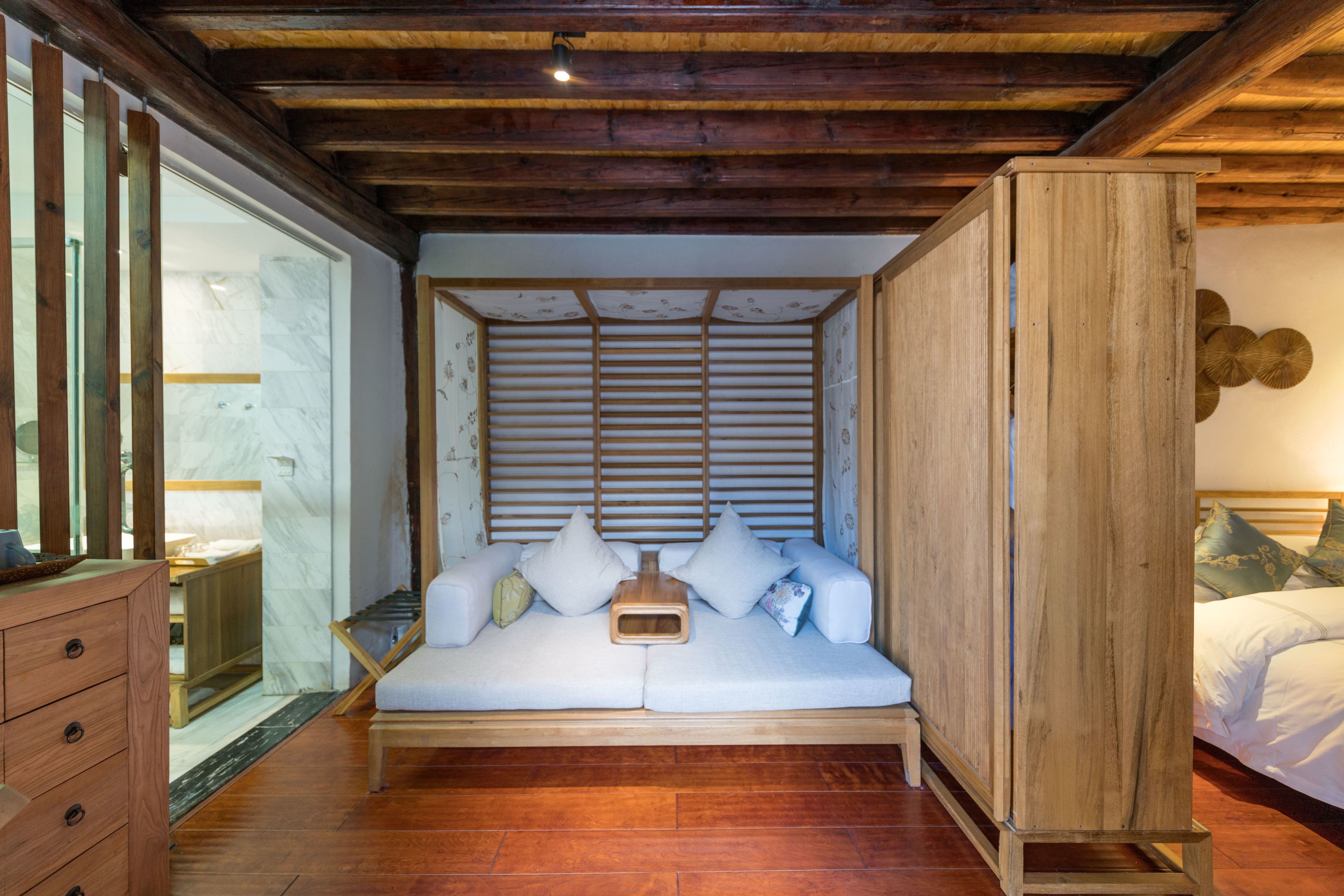 Un dormitorio acogedor con techo de madera, un sofá blanco con cojines y un mueble de madera.