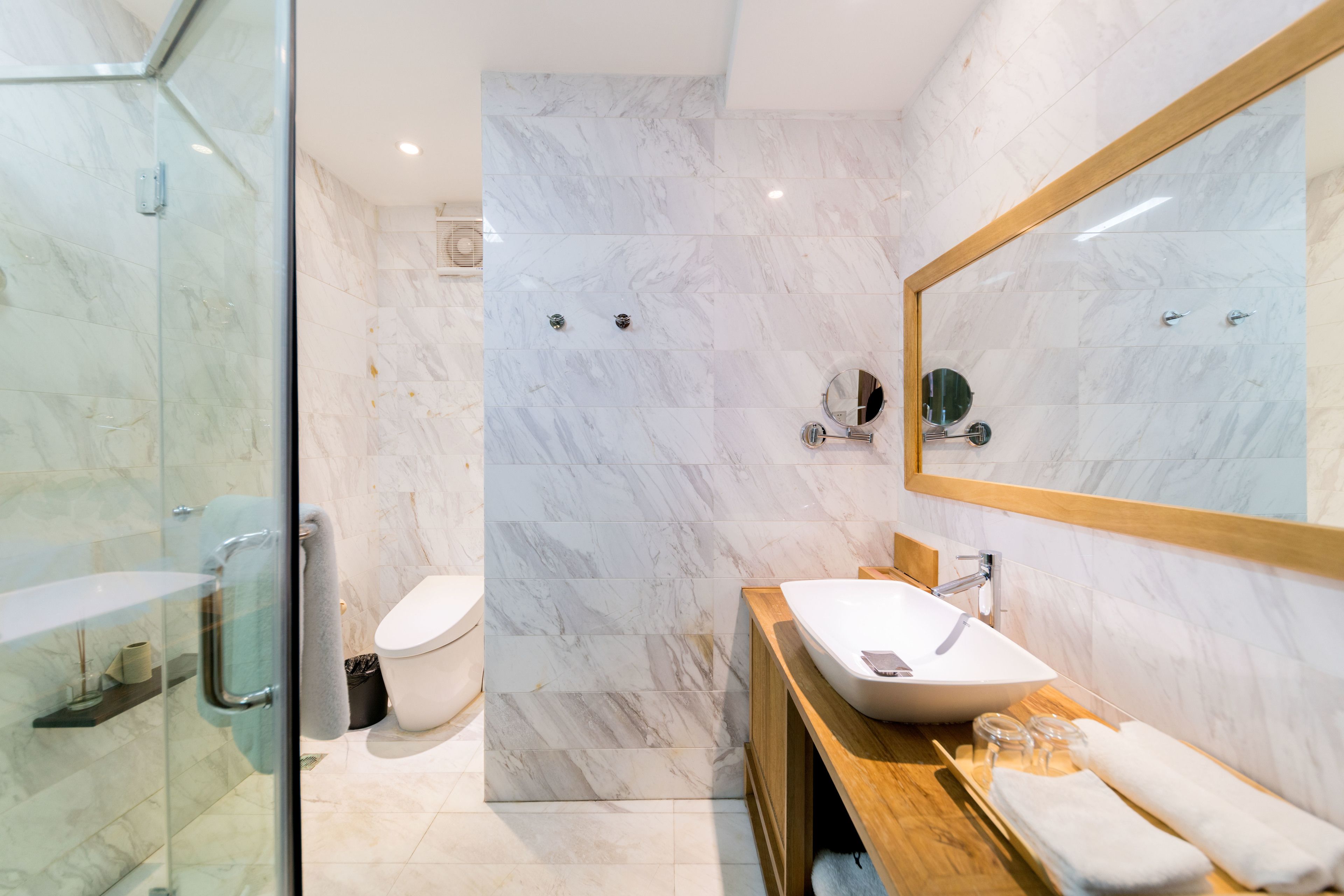 Un baño moderno con cabina de ducha de cristal, un lavabo blanco y un espejo grande.