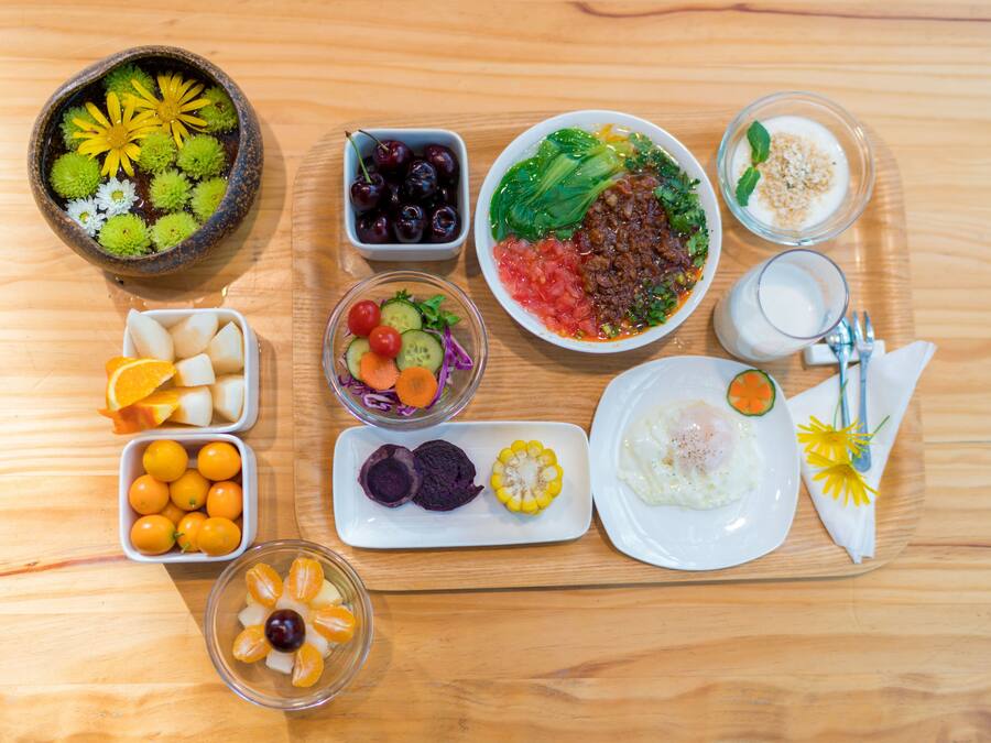 A wooden table with various food items and a glass of milk.