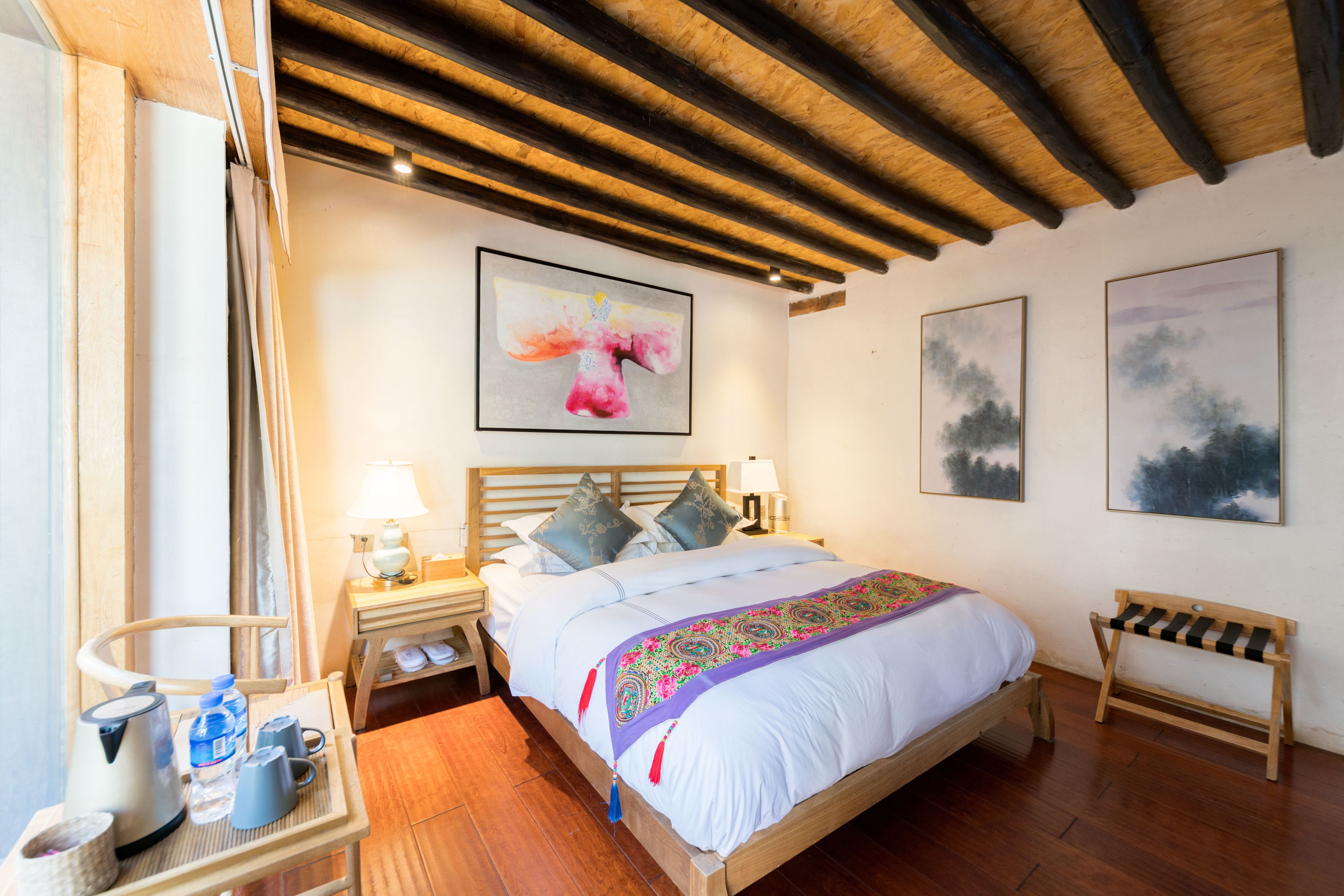 Une chambre à coucher avec un lit en bois, une table de chevet, une petite table de nuit avec une lampe et un banc.