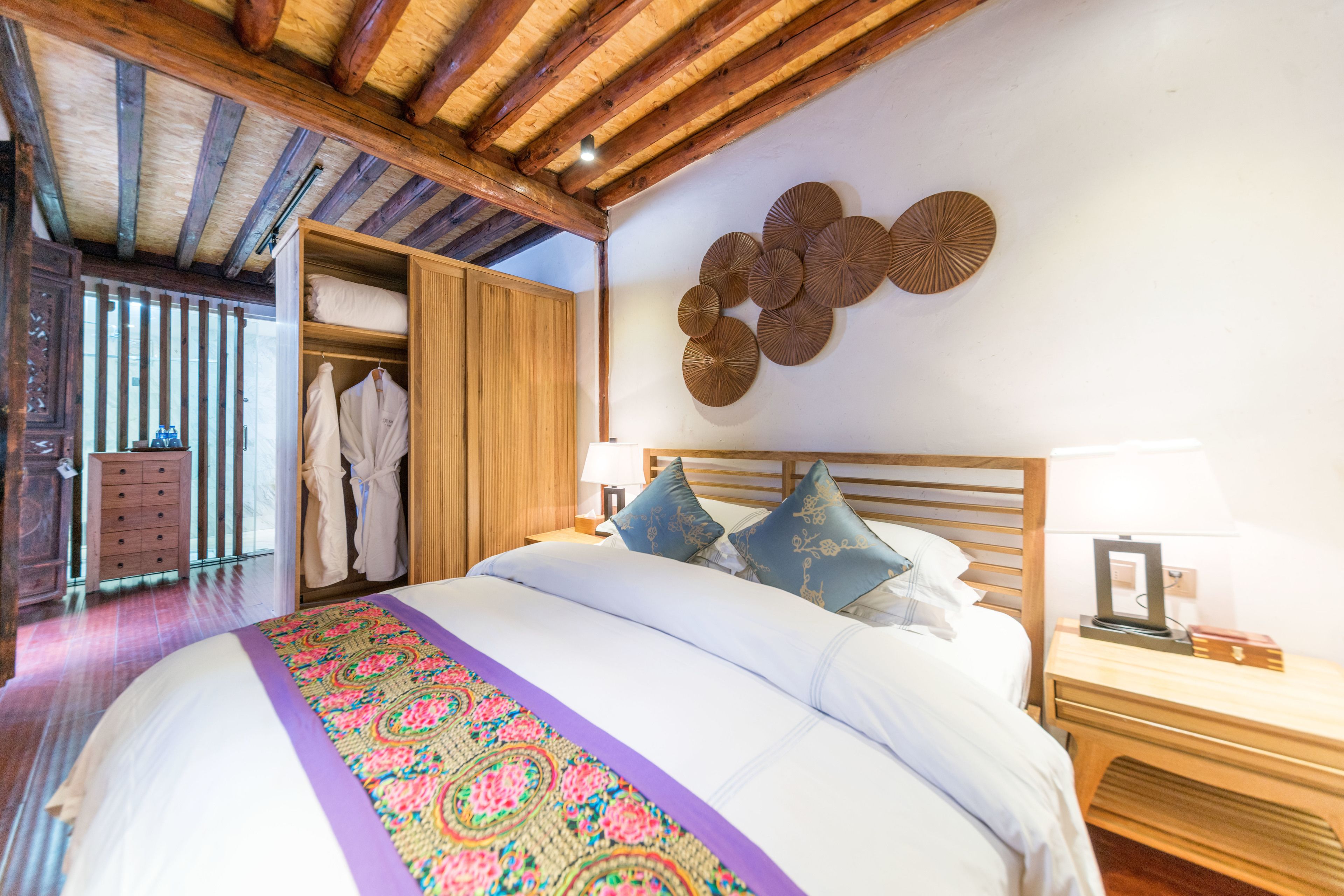 Un dormitorio con una cama grande, vigas de madera en el techo, un armario y un adorno en la pared.