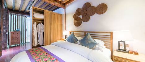 Un dormitorio con una cama grande, vigas de madera en el techo, un armario y un adorno en la pared.