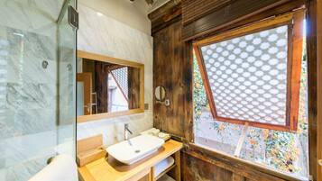 A bathroom with a wooden vanity, a white sink, a mirror, and a window with a lattice design.