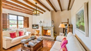 Una sala de estar acogedora con chimenea, vigas de madera y televisor.