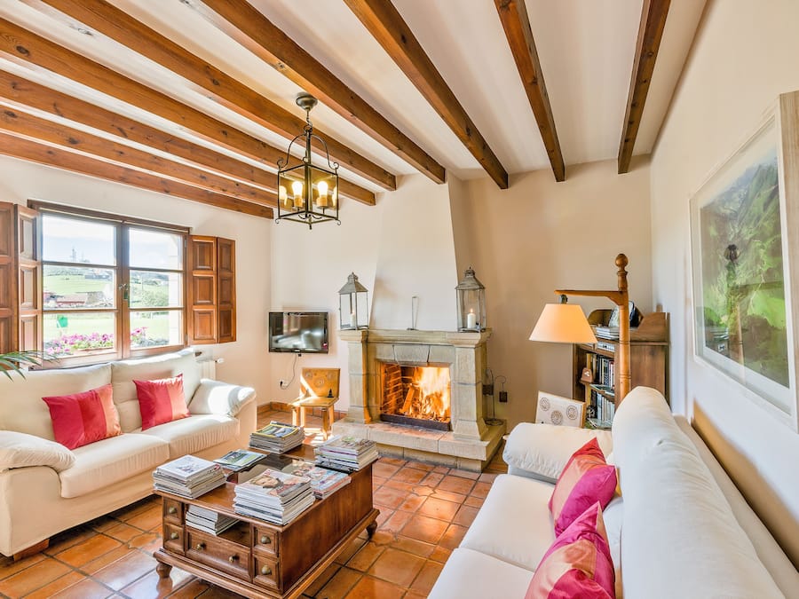 A cozy living room with a fireplace, wooden beams, and a television.