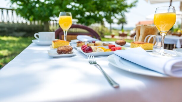 Una mesa de desayuno con diversos alimentos y bebidas, como tostadas, fruta y jugo de naranja.